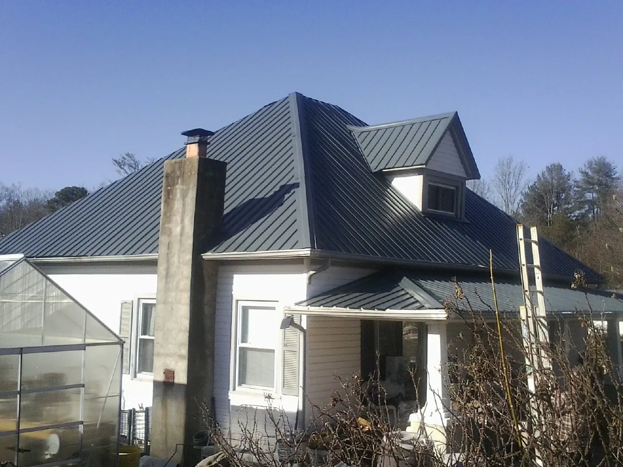 Dark blue standing seam metal roof on a white farmhouse with dormer — Slate & Tile Roof Repair by Roofing Brothers in Somers Point