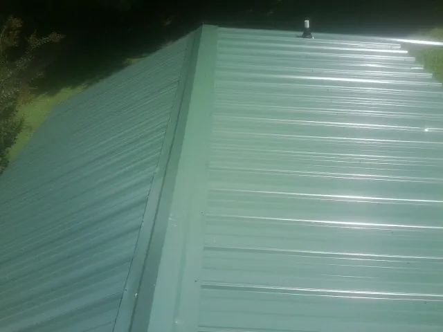 New green metal panels meeting at the ridge of a roof — Flat Roof Repair work by our crew in Somers Point