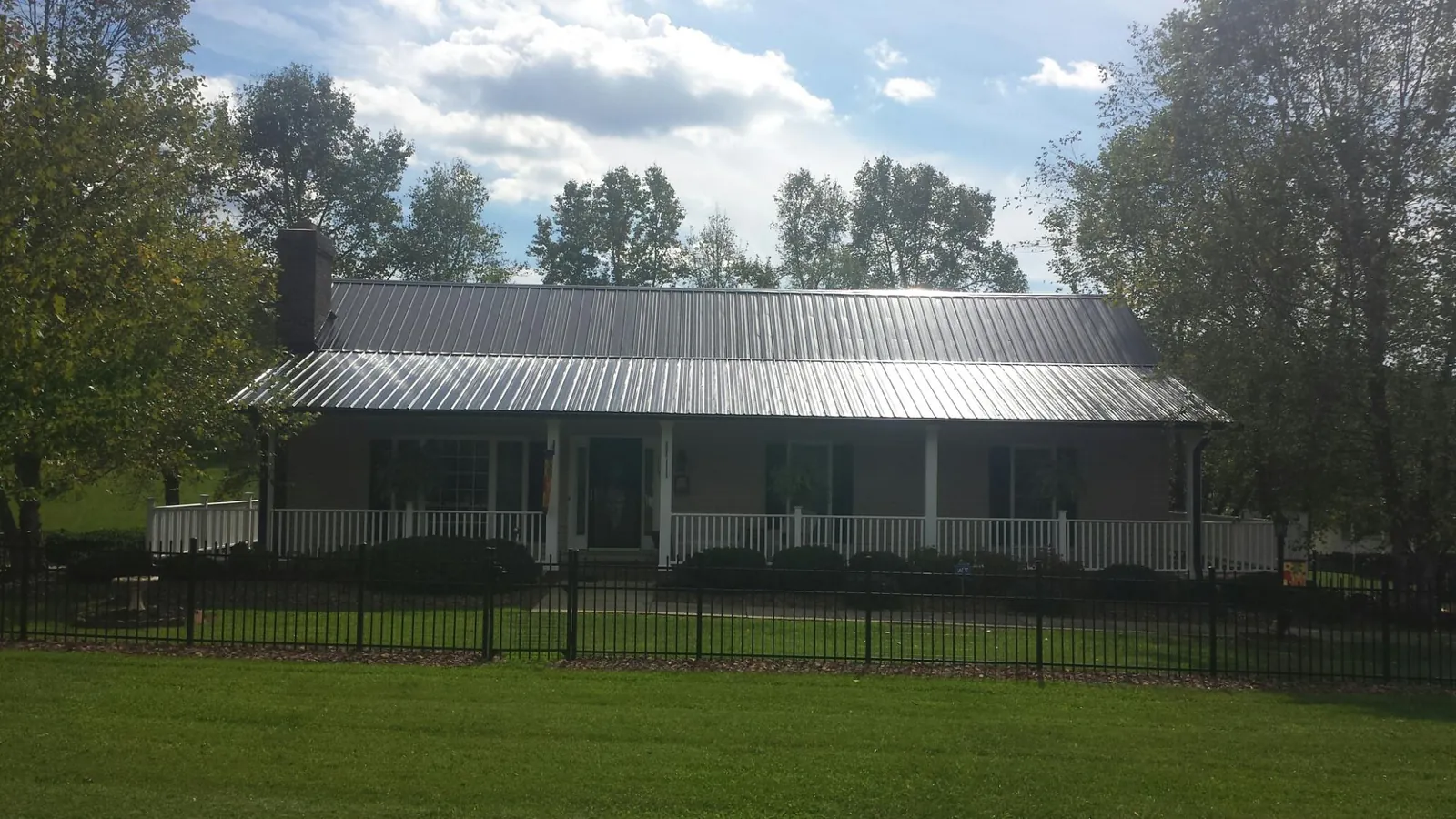 Gray metal roof on a brick ranch with a full width front porch — Gutter Guard Installation work by our crew in Somers Point